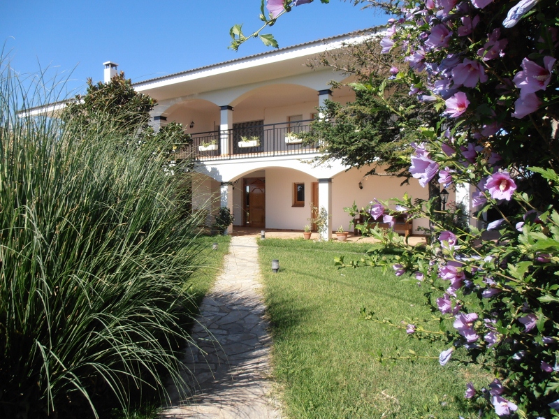 Fachada de la casa con camino de entrada, jardín y flores
