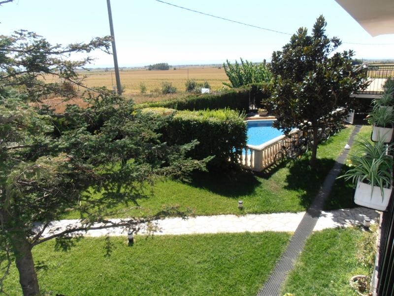 Jardín y piscina vistos desde el balcón, con los campos al fondo