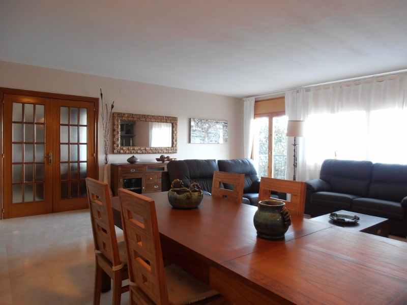 Salón-comedor con mesa de madera y sofás de cuero