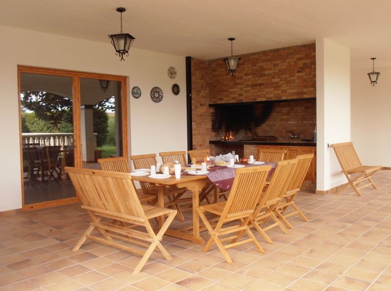 Barbacoa exterior con mesa grande dentro del porche