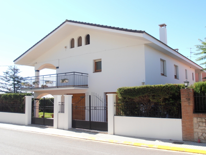 Fachada de la casa vista desde la calle con balcón y valla