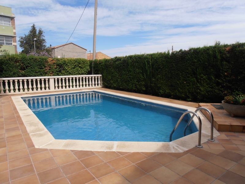 Piscina privada rodeada de seto y jardín