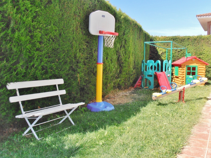 Zona de juegos infantil con canasta, casita y tobogán