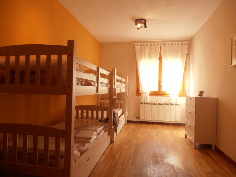 Habitación con literas de madera y pared naranja